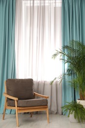 Photo of Comfortable armchair near window with elegant curtains in room