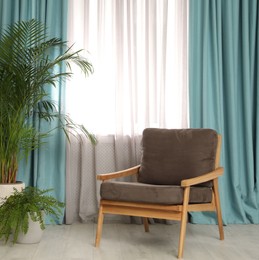 Photo of Comfortable armchair near window with elegant curtains in room