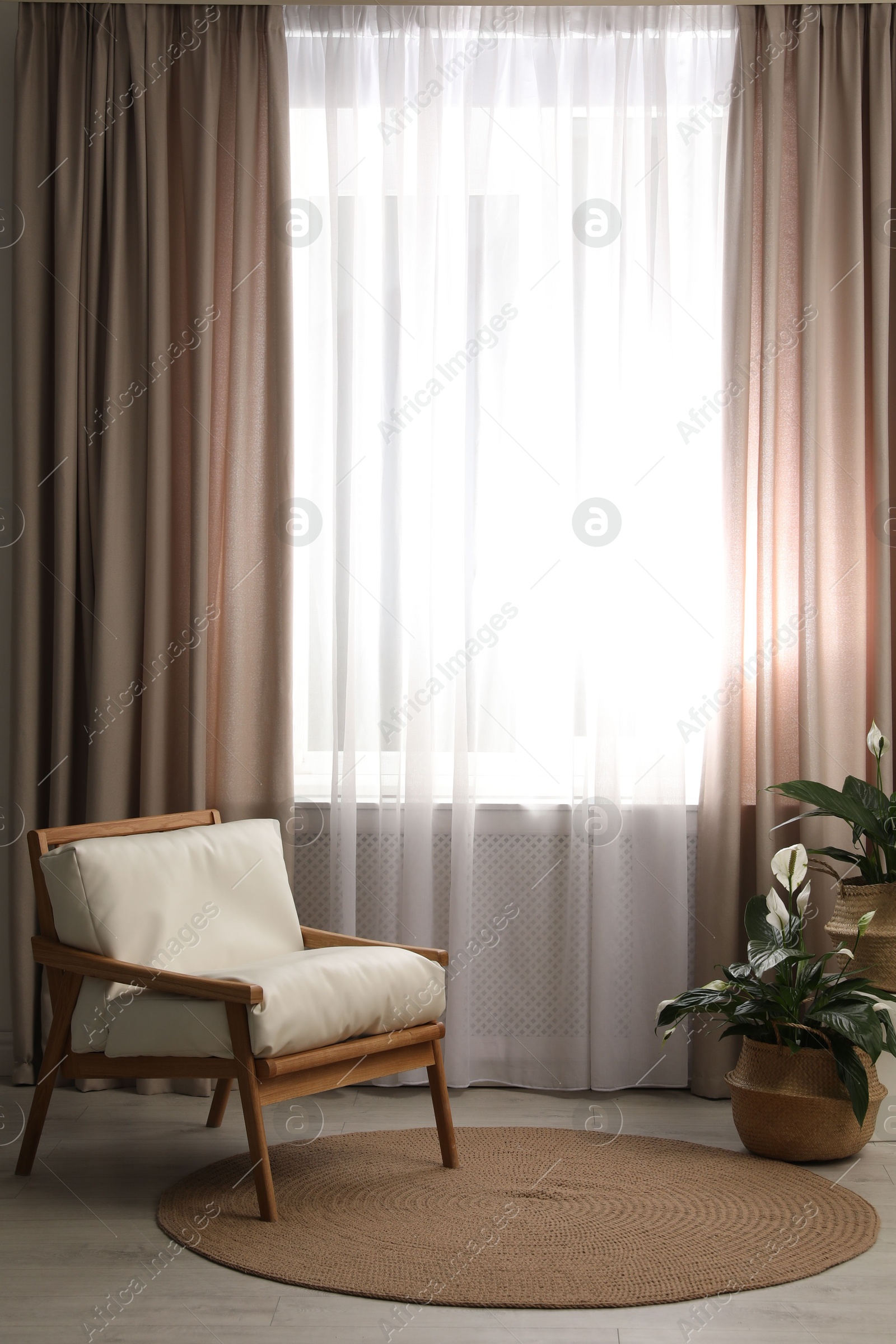 Photo of Comfortable armchair near window with elegant curtains in room