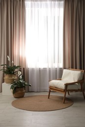 Photo of Comfortable armchair near window with elegant curtains in room