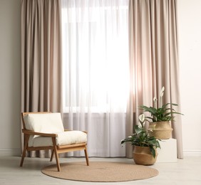Photo of Comfortable armchair near window with elegant curtains in room
