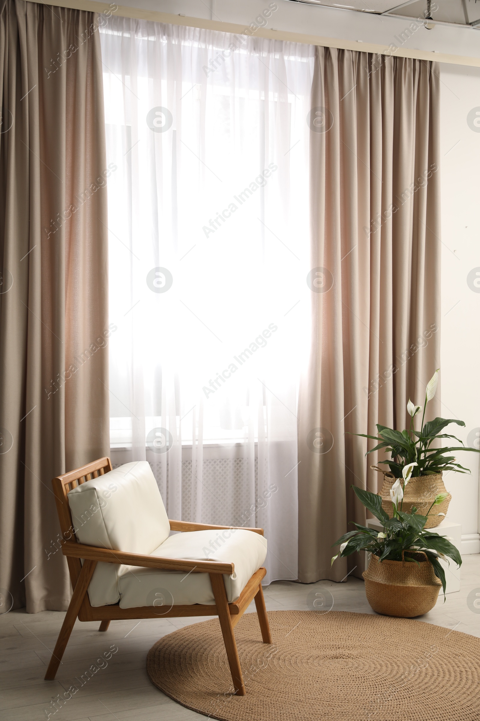 Photo of Comfortable armchair near window with elegant curtains in room
