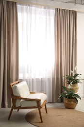 Photo of Comfortable armchair near window with elegant curtains in room