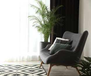 Photo of Comfortable sofa near window with elegant curtains in room. Space for text