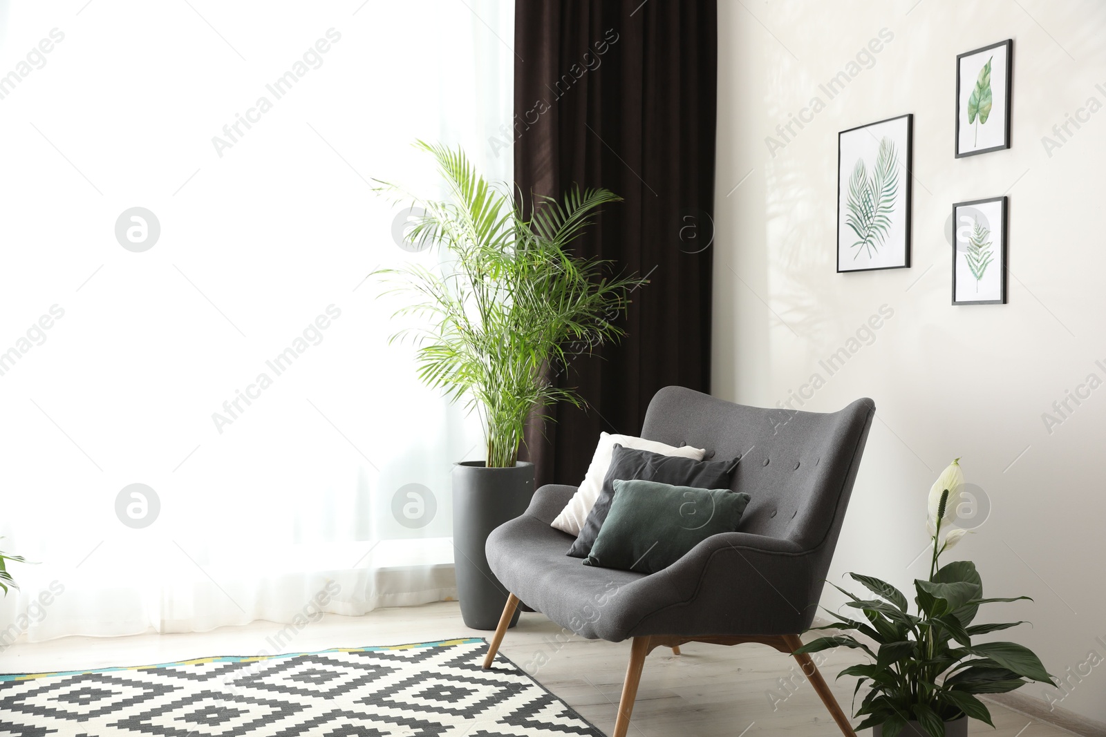 Photo of Comfortable sofa near window with elegant curtains in room. Space for text