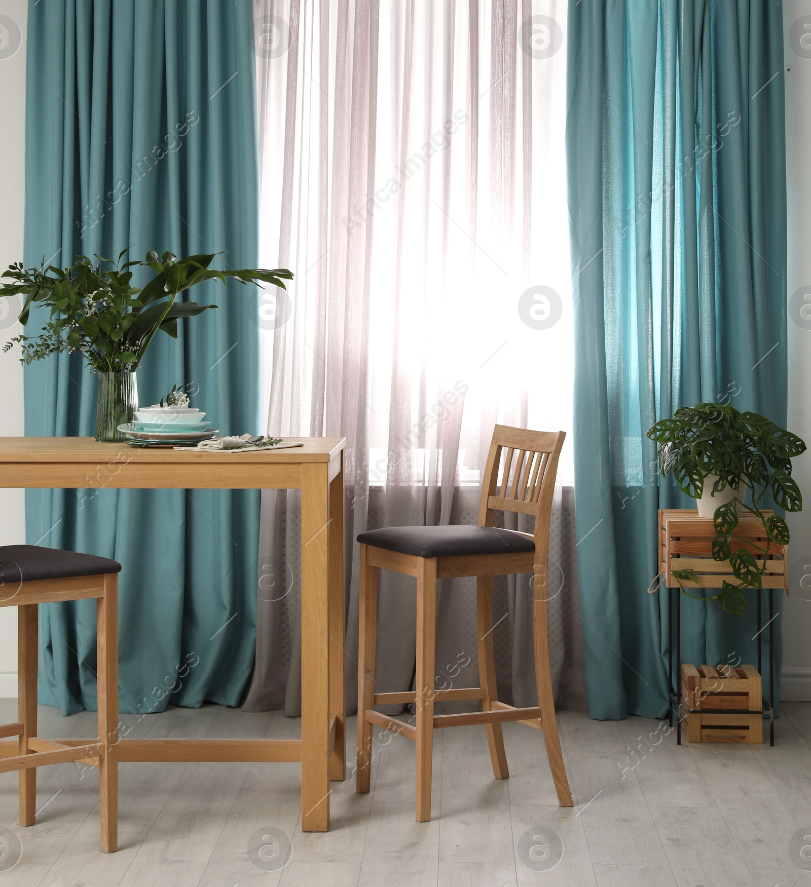 Photo of Stylish wooden table and chairs near window with elegant curtains in room
