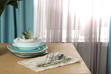 Photo of Dishware on wooden table near window with elegant curtains