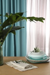 Photo of Dishware on wooden table near window with elegant curtains