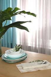 Photo of Dishware on wooden table near window with elegant curtains