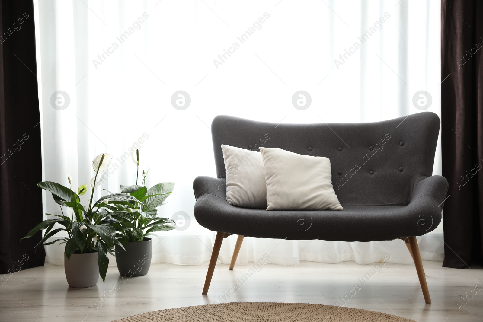 Photo of Comfortable sofa near window with elegant curtains in room