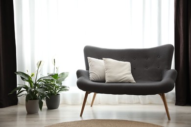 Photo of Comfortable sofa near window with elegant curtains in room