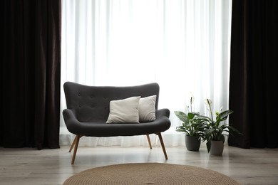 Photo of Comfortable sofa near window with elegant curtains in room