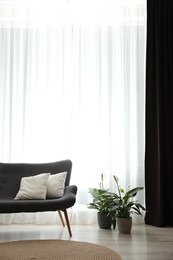 Photo of Comfortable sofa near window with elegant curtains in room