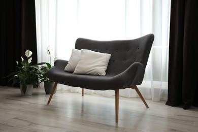 Photo of Comfortable sofa near window with elegant curtains in room
