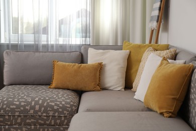 Photo of Comfortable sofa near window with stylish curtains in living room