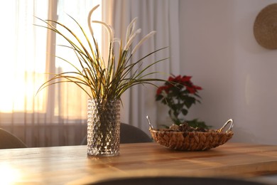 Photo of Vase on wooden table near window with curtains in room