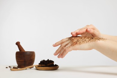 Photo of Woman applying body scrub onto her hand on white background, closeup