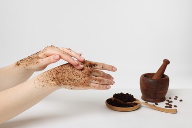 Photo of Woman applying body scrub onto her hand on white background, closeup