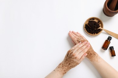 Photo of Woman applying body scrub onto her hand on white background, top view. Space for text