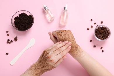 Photo of Woman applying body scrub onto her hand on pink background, top view