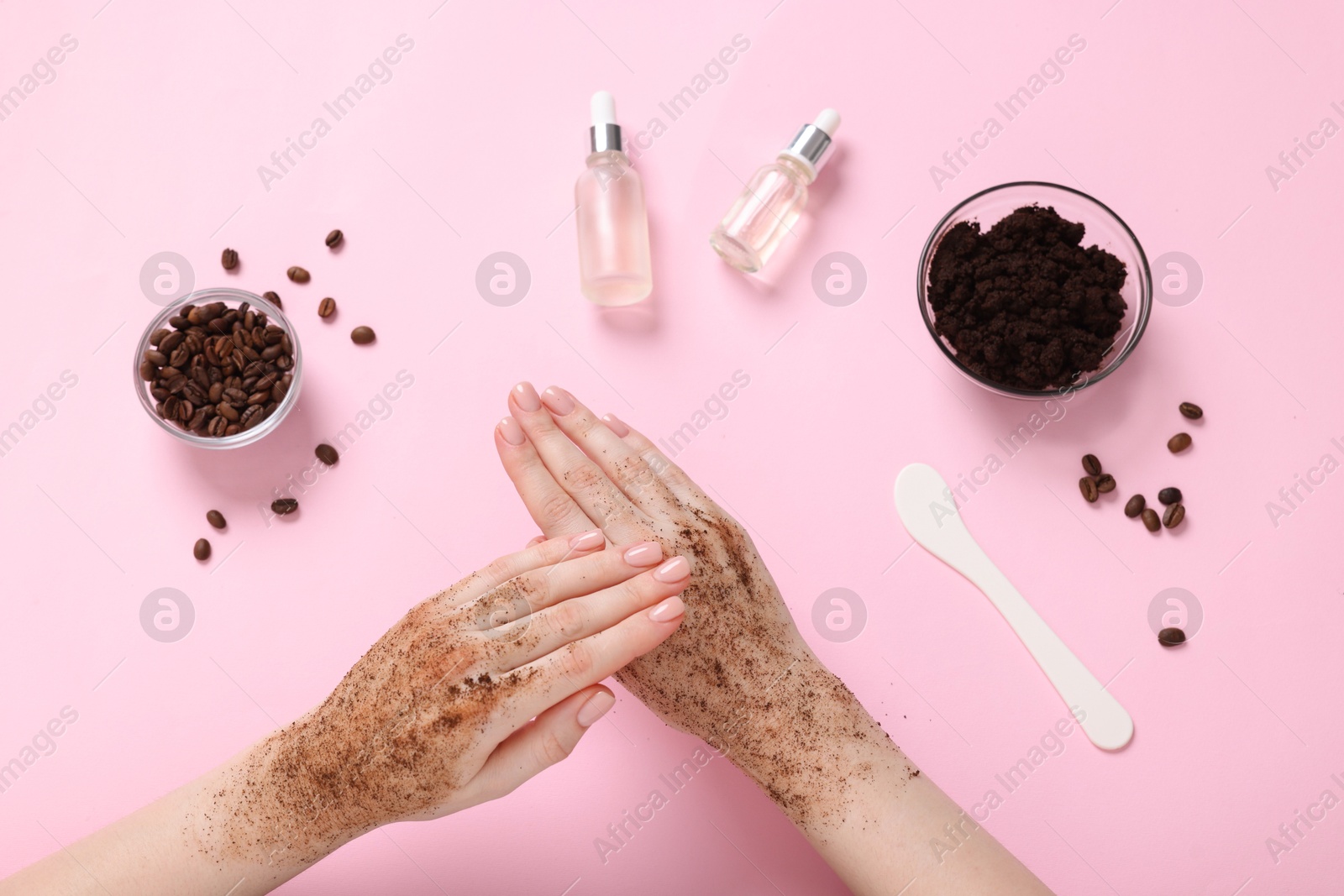 Woman applying body scrub onto her hand on pink background, top view Photo of Woman applying body scrub onto her hand on pink background, top view