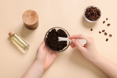 Photo of Woman with bowl of body scrub on beige background, top view