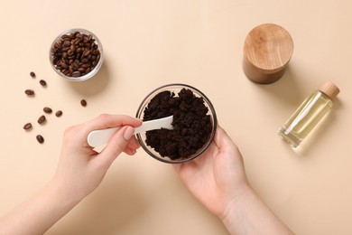 Photo of Woman with bowl of body scrub on beige background, top view