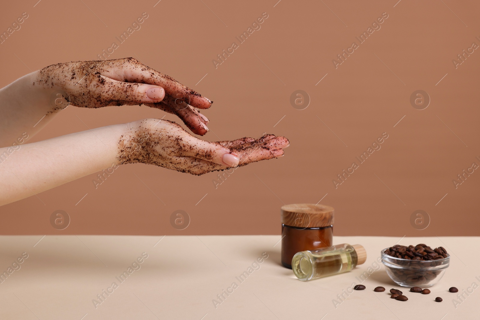 Woman applying body scrub onto her hand against dark beige background, closeup Photo of Woman applying body scrub onto her hand against dark beige background, closeup