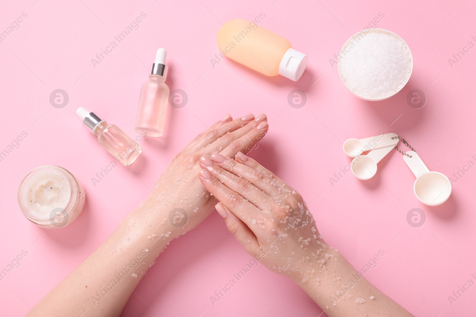 Woman applying body scrub onto her hand on pink background, top view Photo of Woman applying body scrub onto her hand on pink background, top view