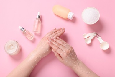 Photo of Woman applying body scrub onto her hand on pink background, top view