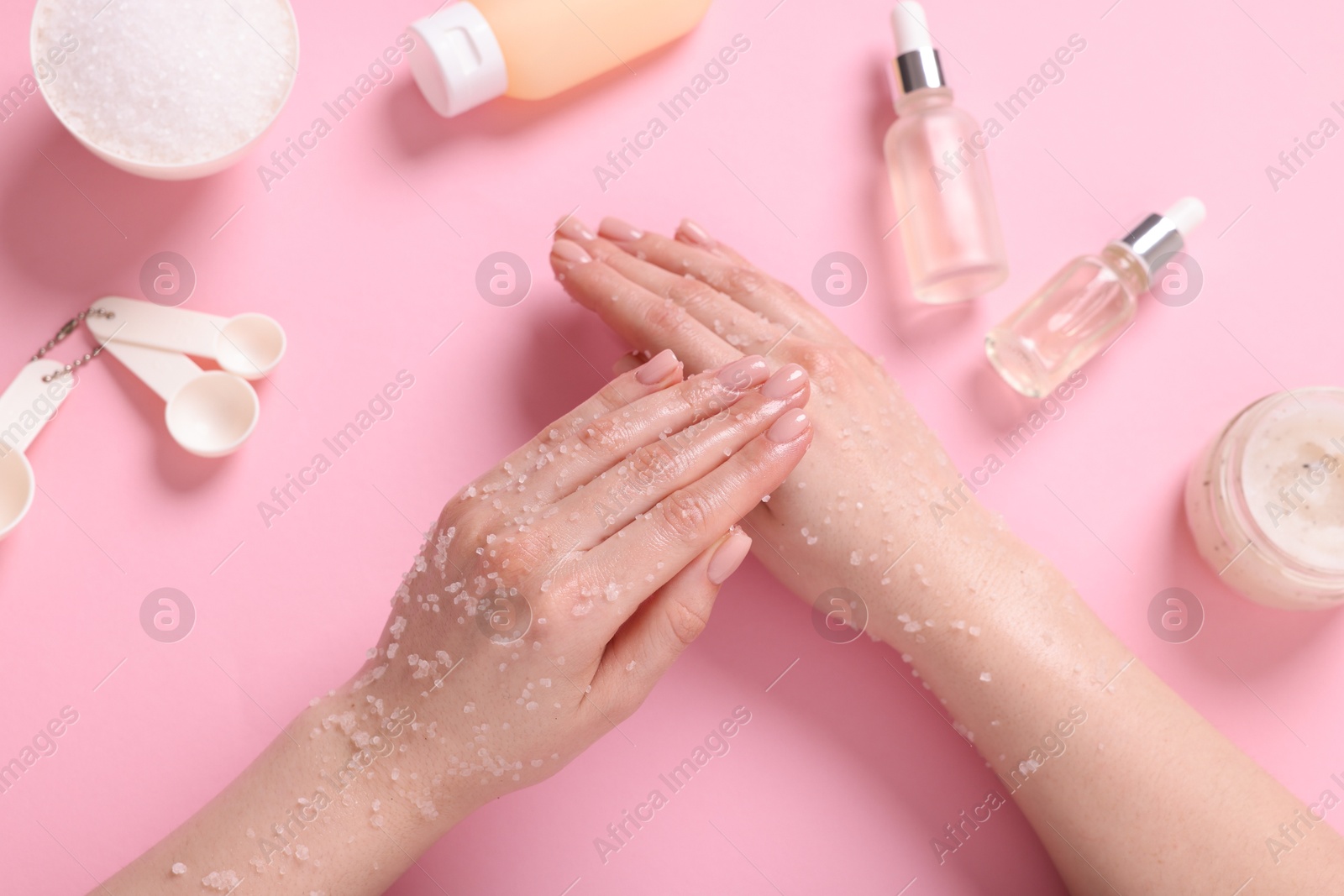 Woman applying body scrub onto her hand on pink background, top view Photo of Woman applying body scrub onto her hand on pink background, top view