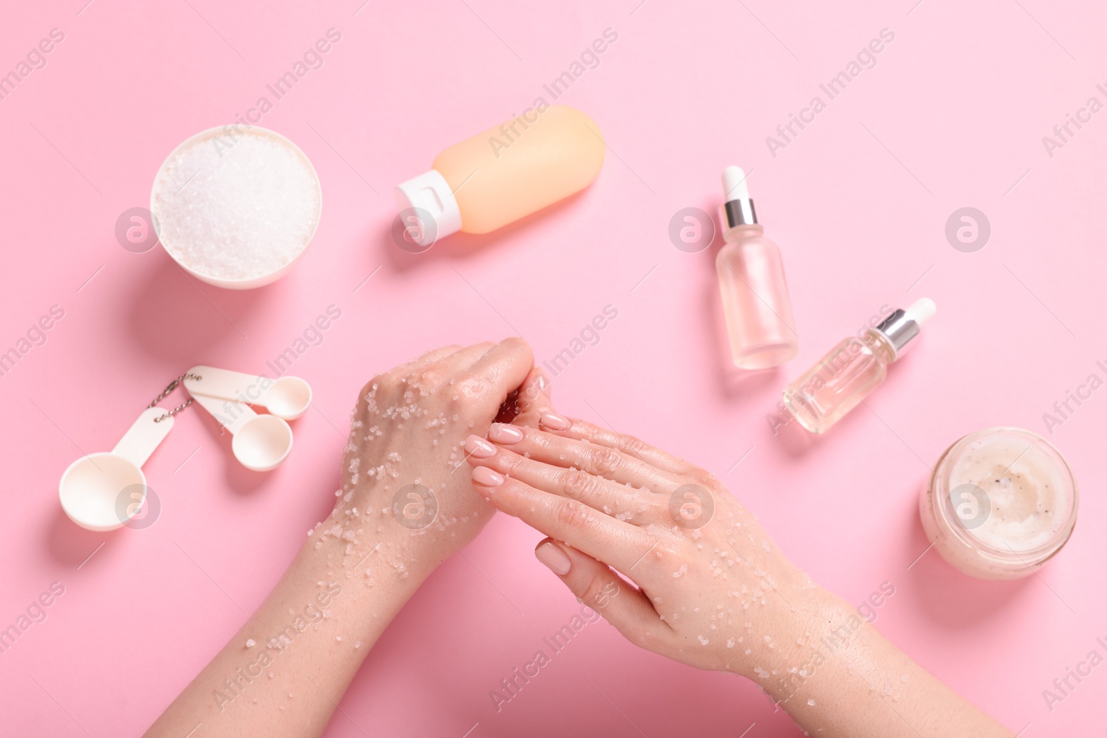 Woman applying body scrub onto her hand on pink background, top view Photo of Woman applying body scrub onto her hand on pink background, top view