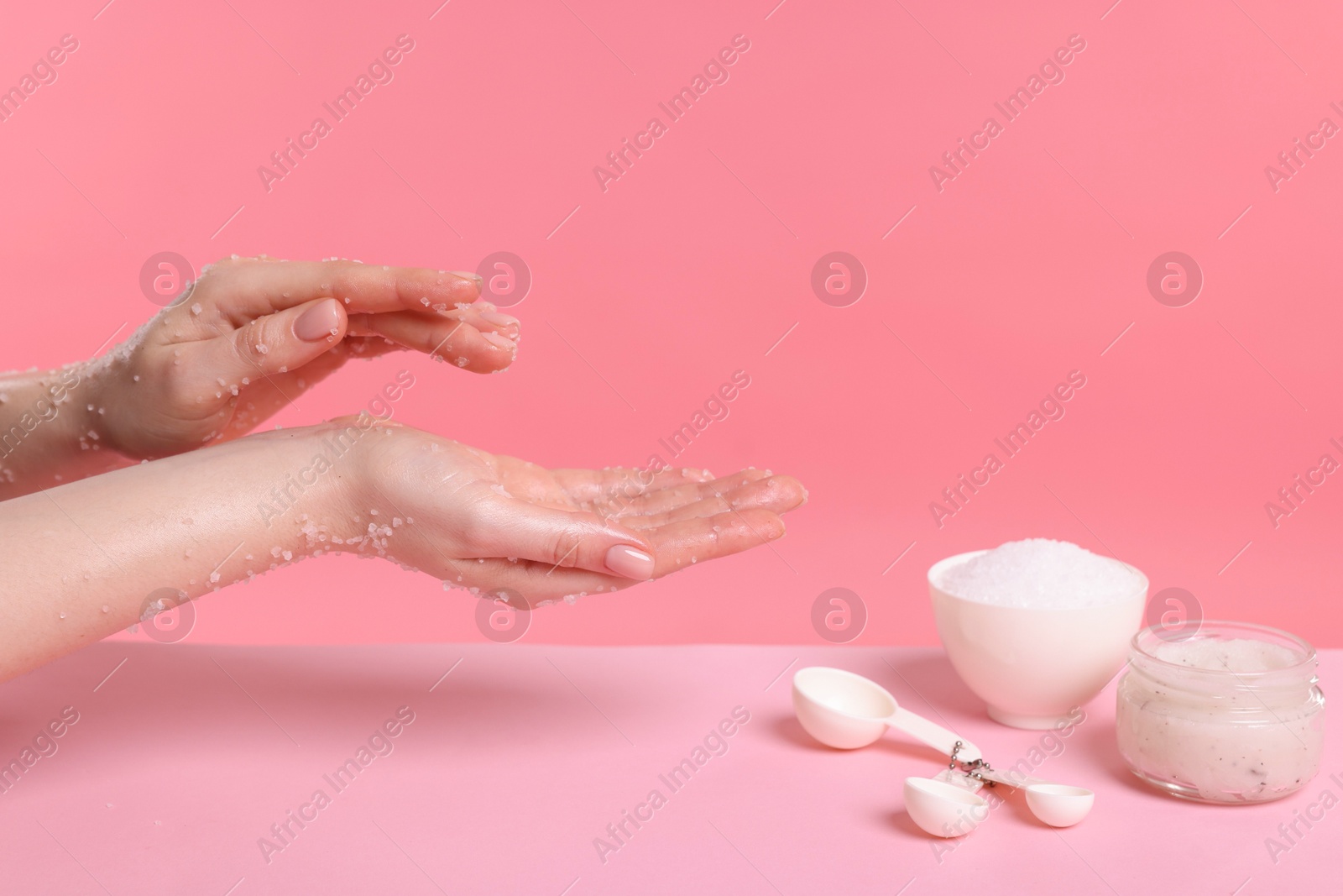 Woman applying body scrub onto her hand against pink background, closeup Photo of Woman applying body scrub onto her hand against pink background, closeup
