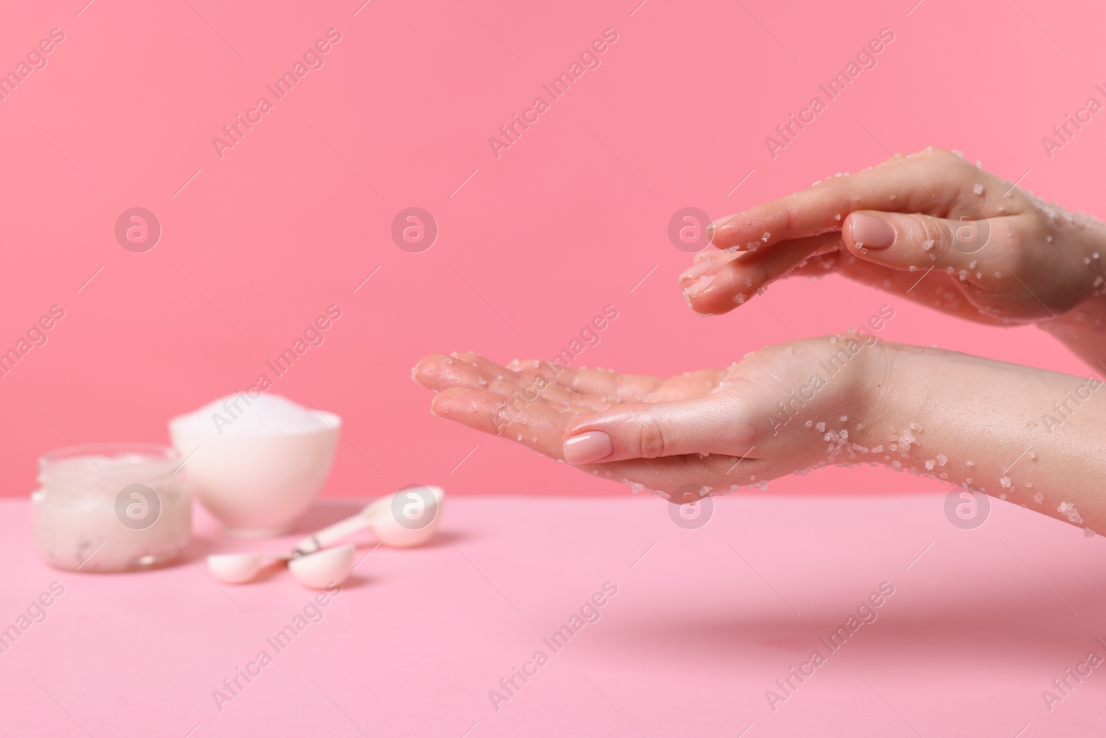 Woman applying body scrub onto her hand against pink background, closeup Photo of Woman applying body scrub onto her hand against pink background, closeup