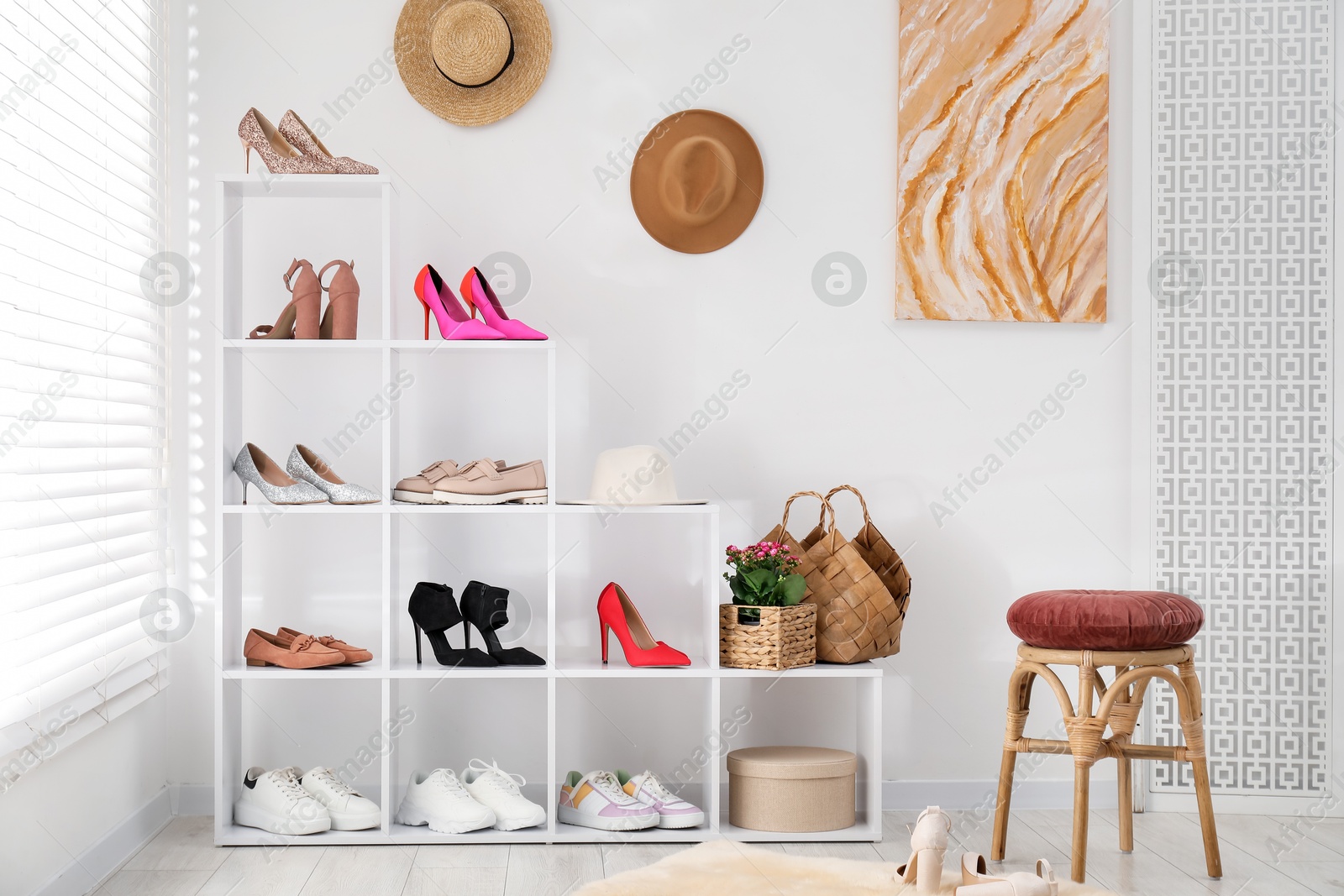 Shoe storage. Shelving unit with different footwear and stool near white wall indoors Photo of Shoe storage. Shelving unit with different footwear and stool near white wall indoors