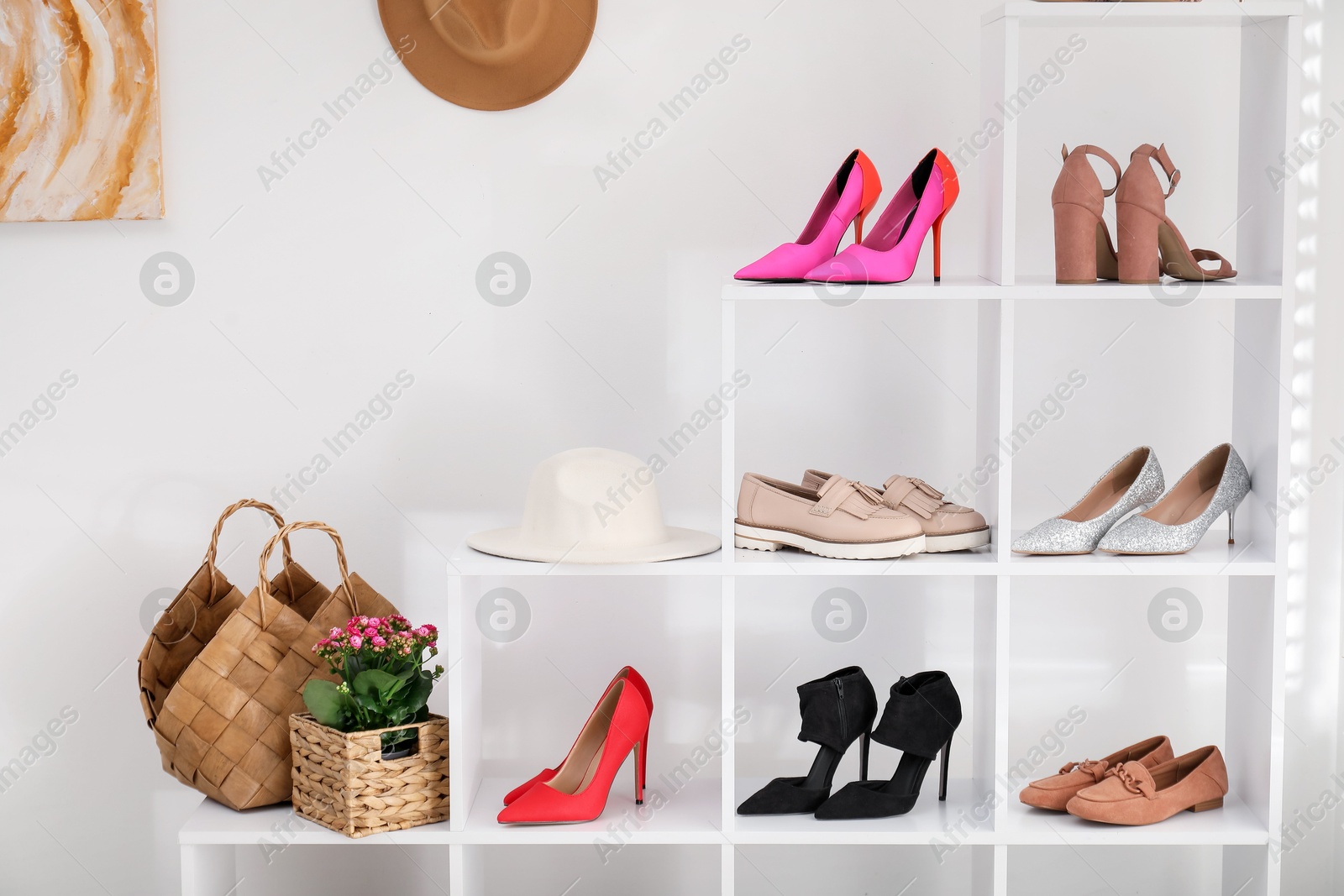 Shoe storage. Shelving unit with different footwear and decor near white wall indoors Photo of Shoe storage. Shelving unit with different footwear and decor near white wall indoors