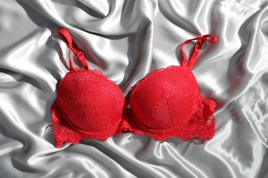 Photo of Lace bra on light grey silk fabric, top view