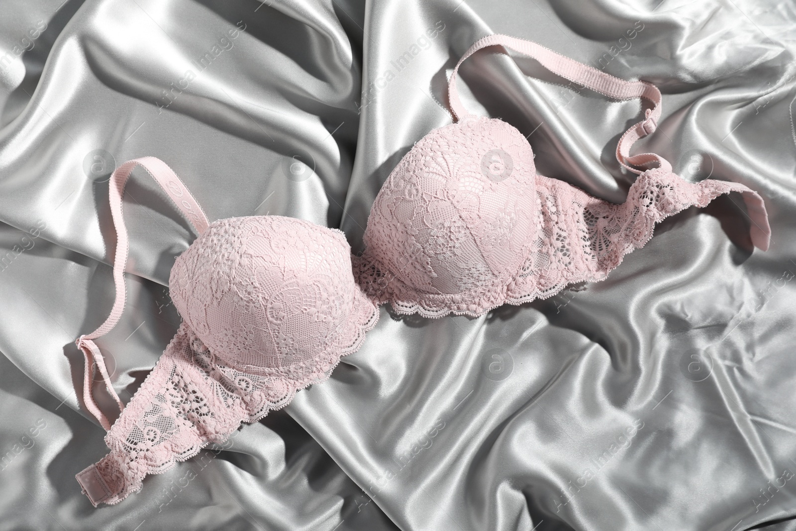 Photo of Lace bra on light grey silk fabric, top view