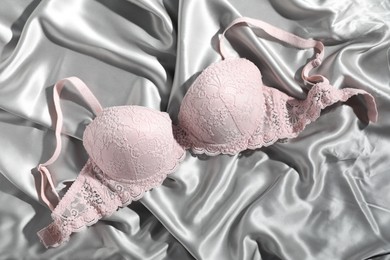 Photo of Lace bra on light grey silk fabric, top view