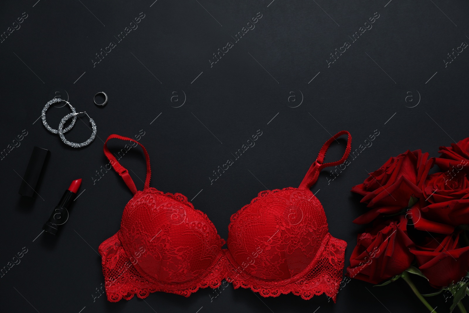 Red bra, jewelry, roses and lipstick on black background, flat lay. Space for text Photo of Red bra, jewelry, roses and lipstick on black background, flat lay. Space for text
