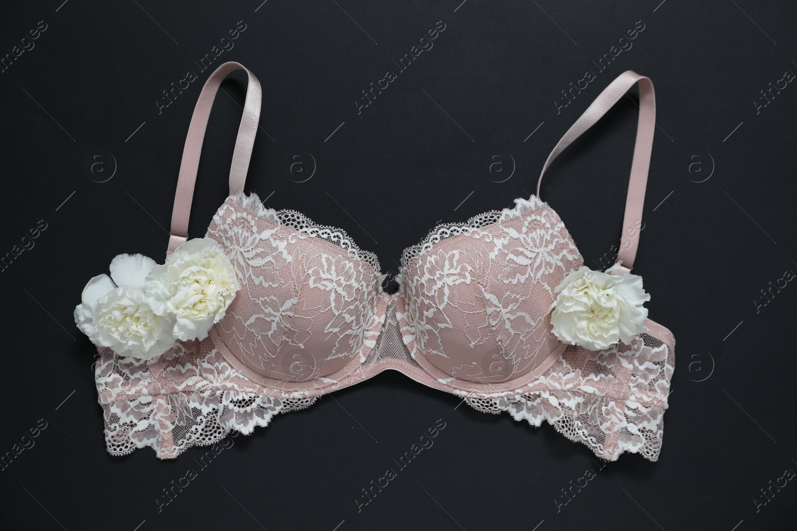 Lace bra and beautiful flowers on black background, flat lay Photo of Lace bra and beautiful flowers on black background, flat lay