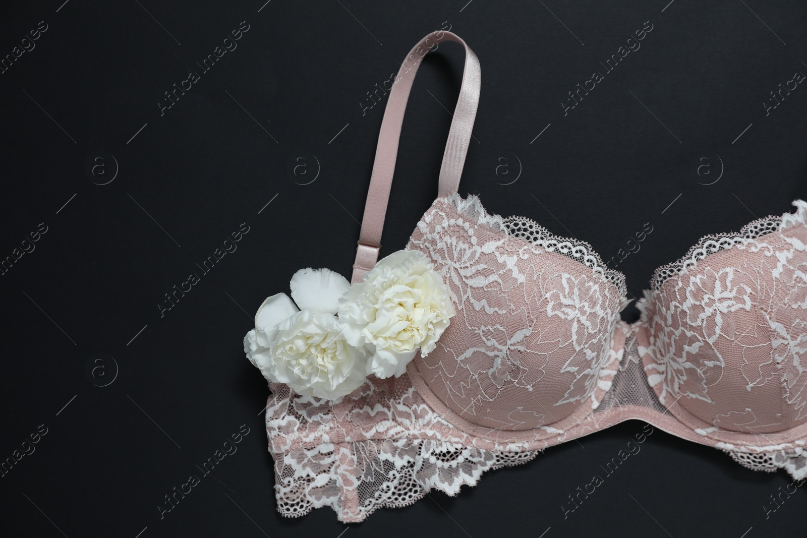 Lace bra and beautiful flowers on black background, flat lay. Space for text Photo of Lace bra and beautiful flowers on black background, flat lay. Space for text