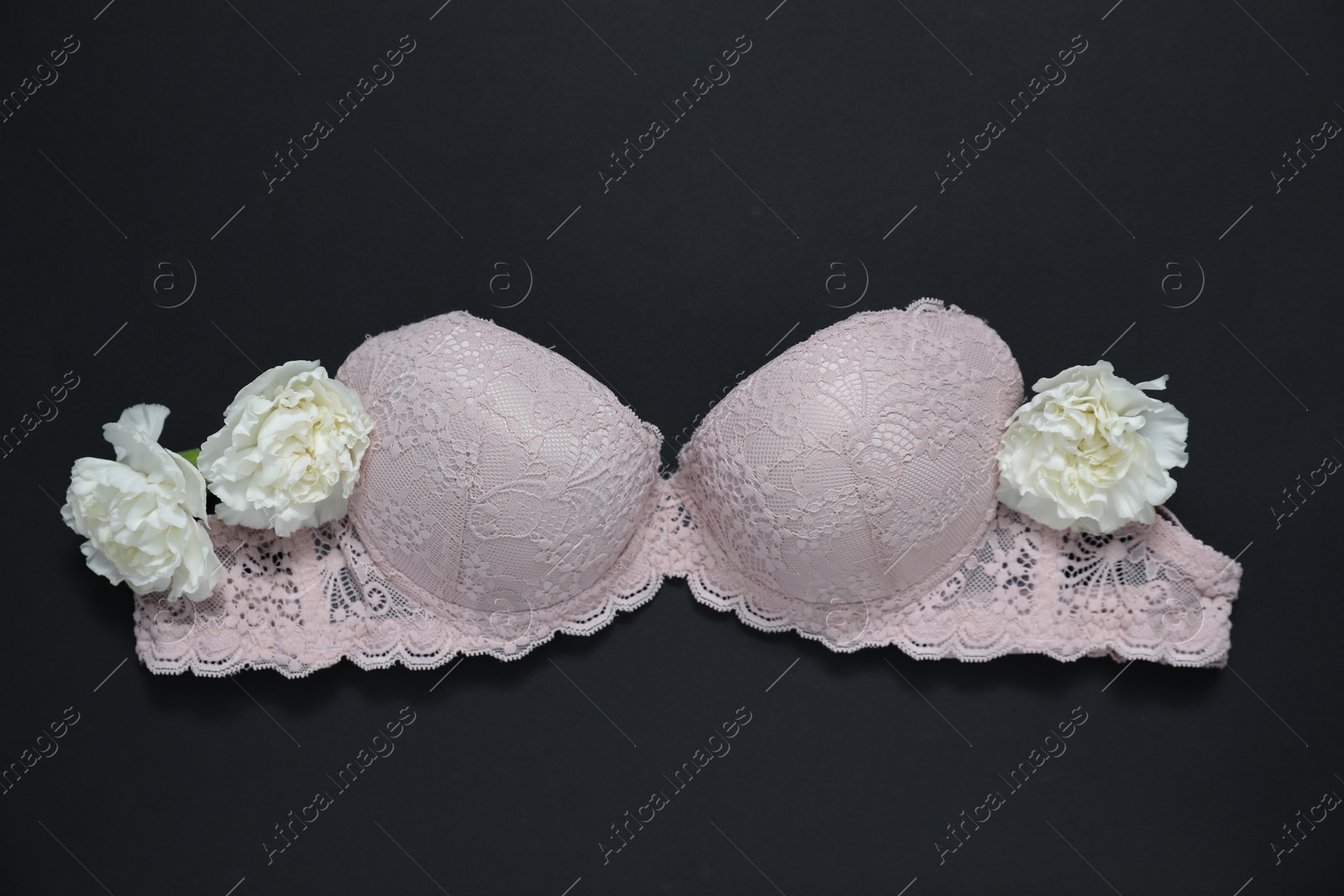 Lace bra and beautiful flowers on black background, flat lay Photo of Lace bra and beautiful flowers on black background, flat lay