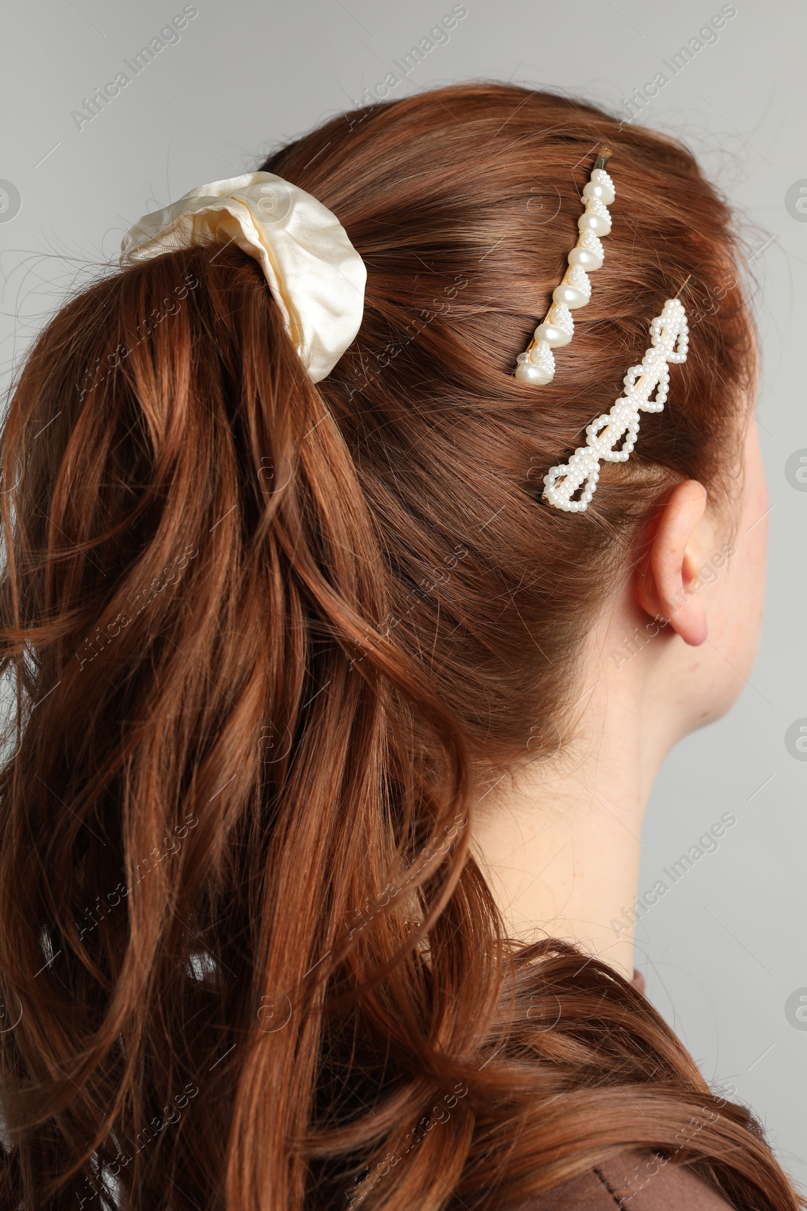 Woman with beautiful hair accessories on light grey background Photo of Woman with beautiful hair accessories on light grey background