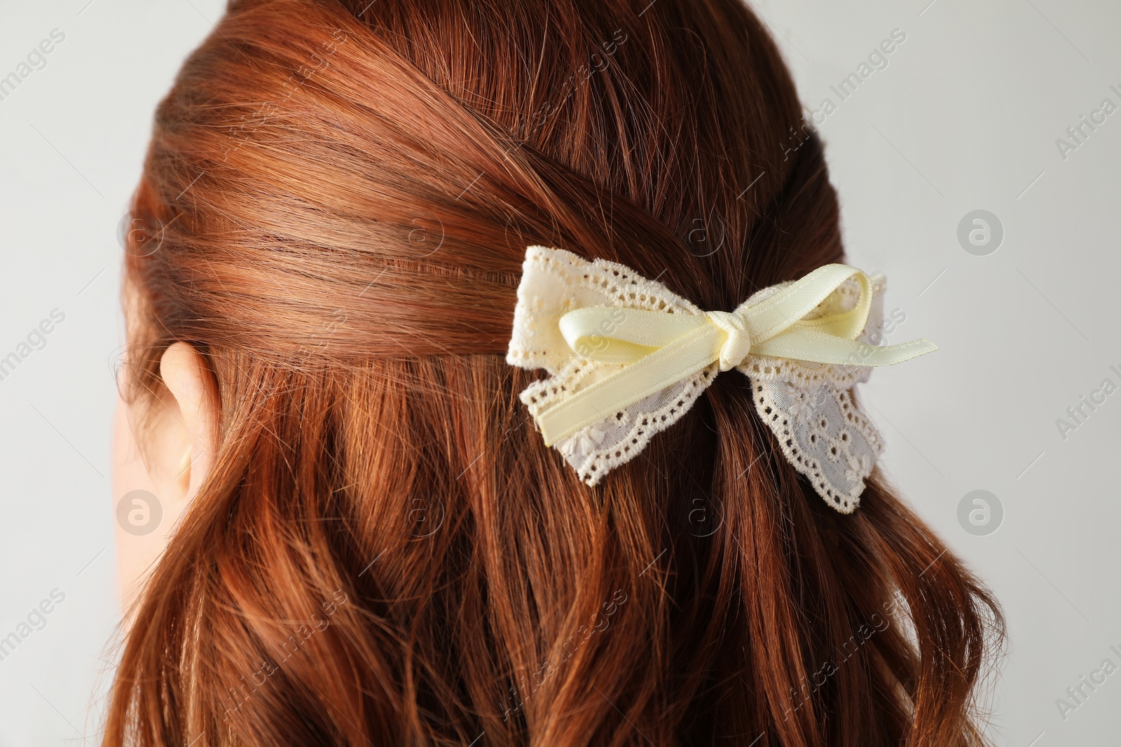 Woman with beautiful hair bow on light grey background, closeup Photo of Woman with beautiful hair bow on light grey background, closeup