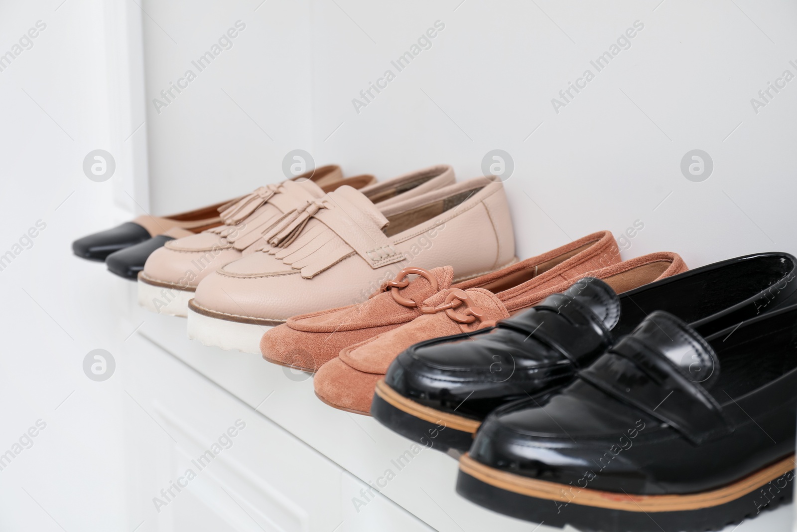 Shoe storage. Different footwear on shelf indoors, closeup Photo of Shoe storage. Different footwear on shelf indoors, closeup