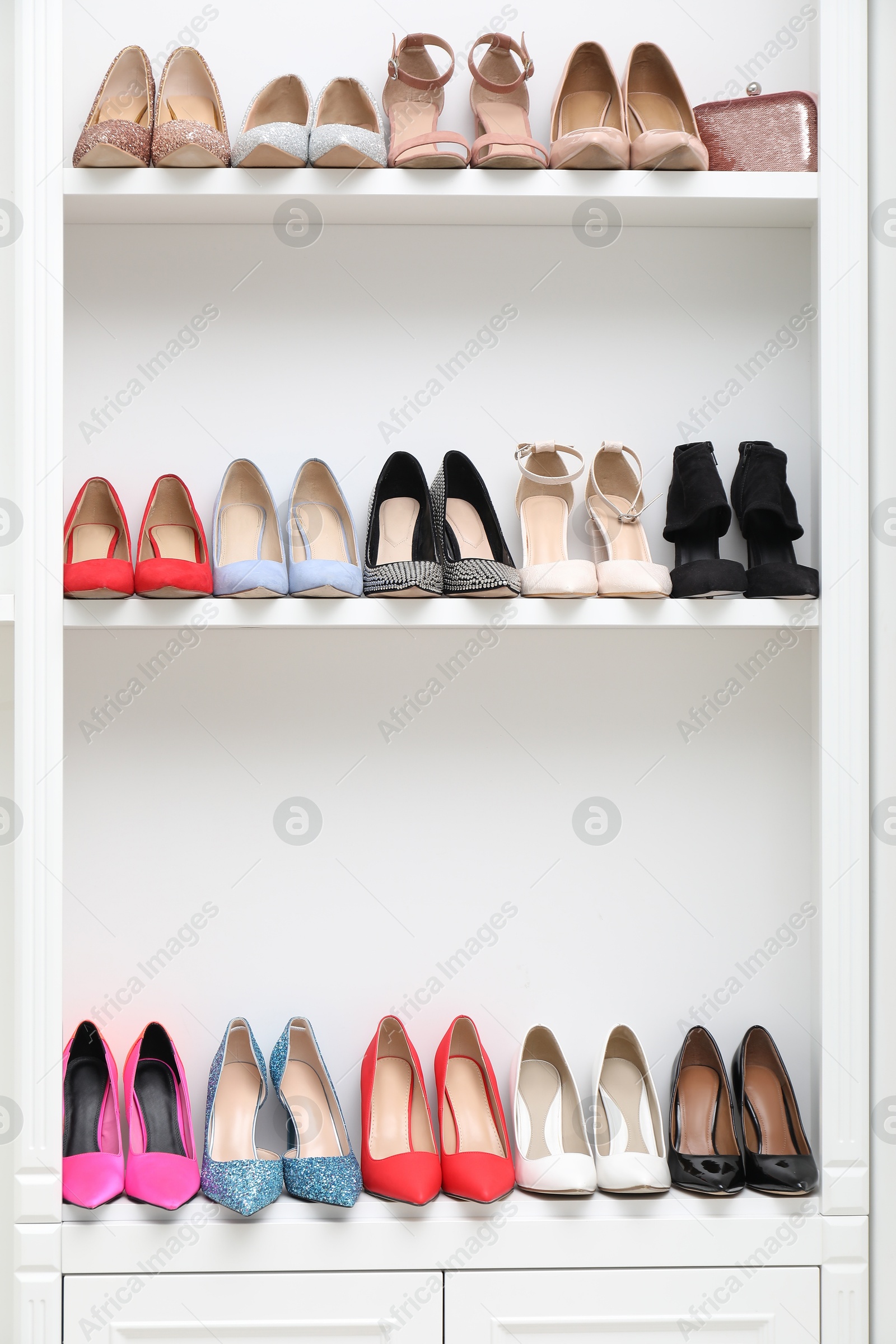 Shoe storage. Different high heeled shoes and bag on shelves indoors Photo of Shoe storage. Different high heeled shoes and bag on shelves indoors
