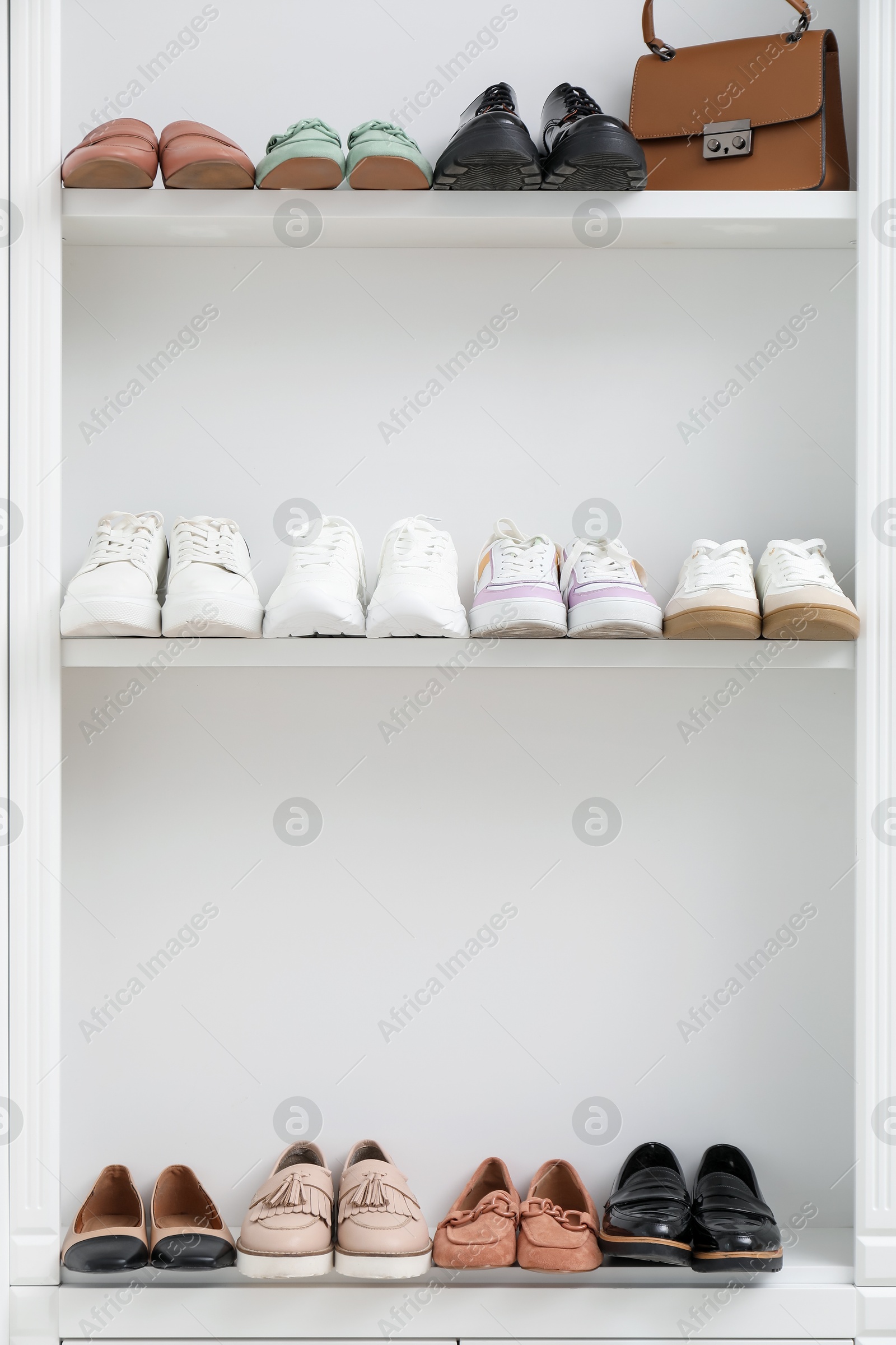 Shoe storage. Different footwear and bag on shelves indoors Photo of Shoe storage. Different footwear and bag on shelves indoors
