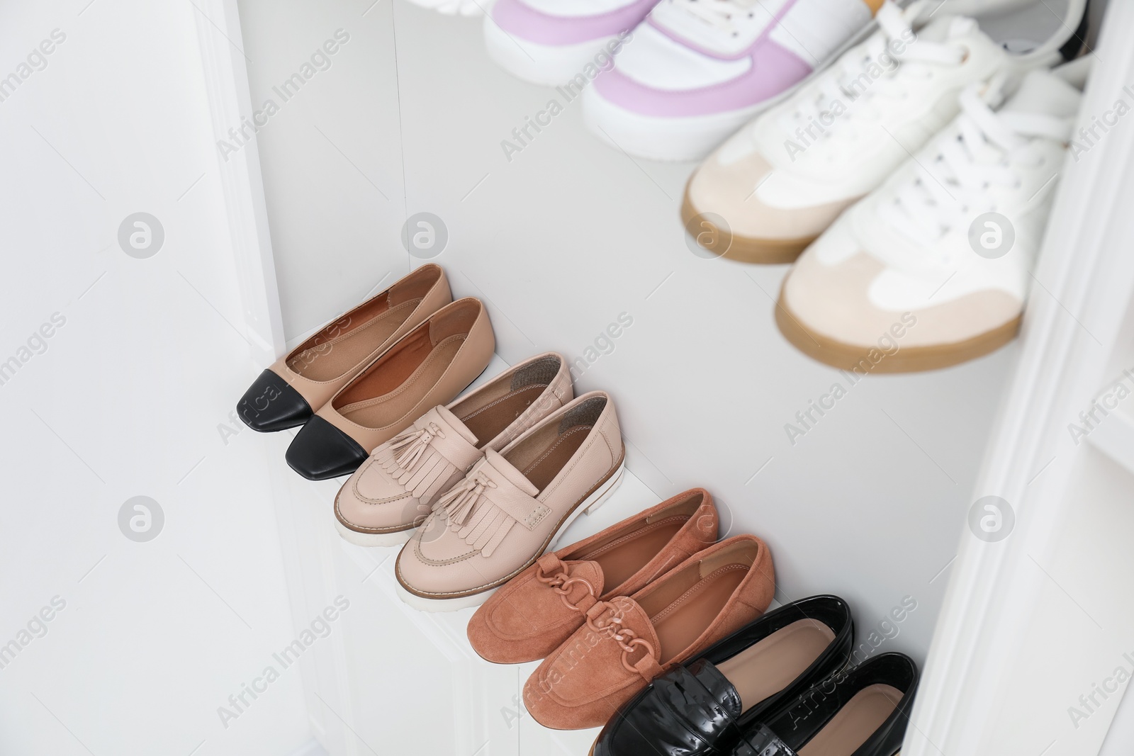 Shoe storage. Different footwear on shelves indoors, closeup Photo of Shoe storage. Different footwear on shelves indoors, closeup