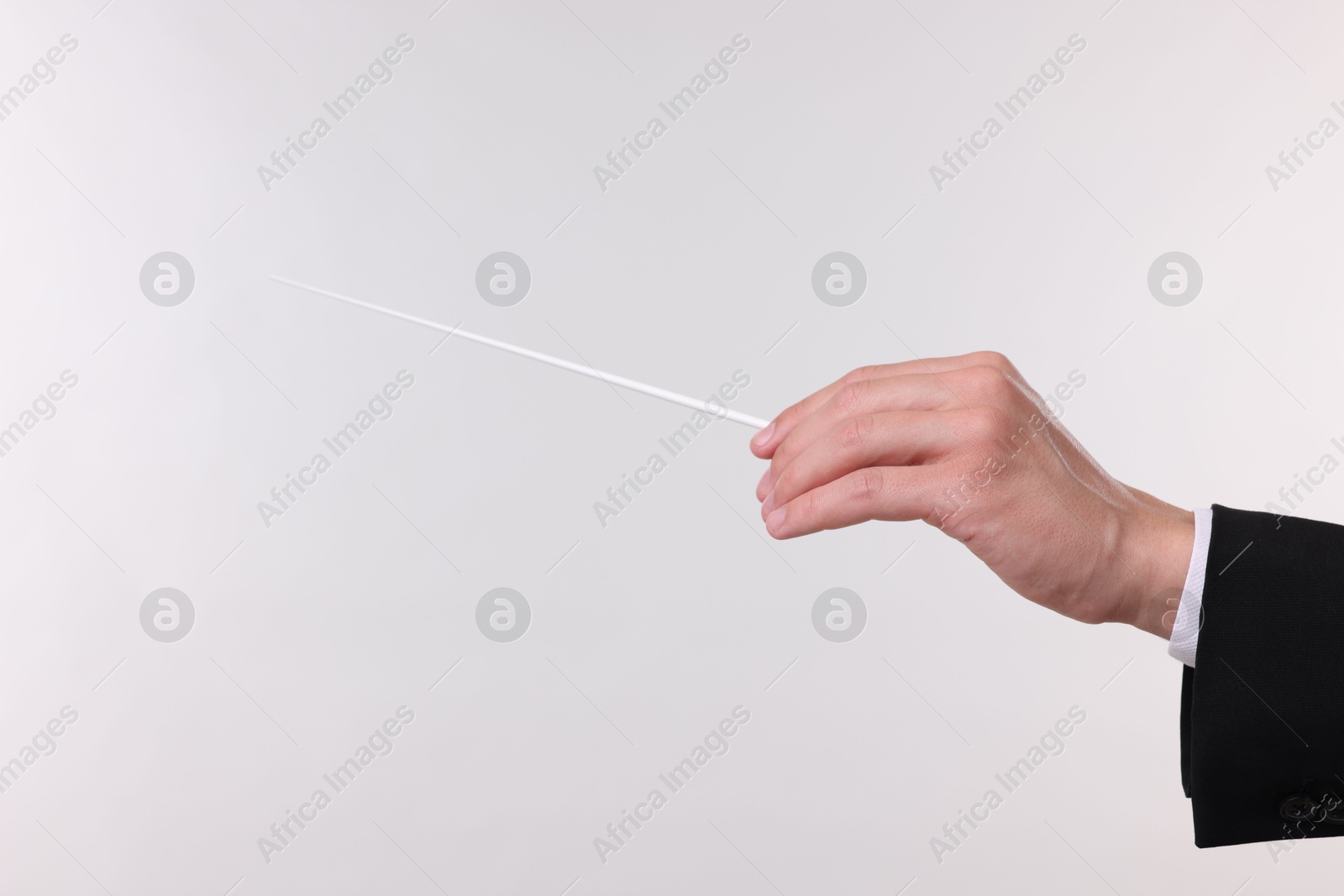 Conductor with baton on light grey background, closeup Photo of Conductor with baton on light grey background, closeup
